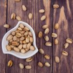 top-view-pistachios-white-bowl-wooden-surface